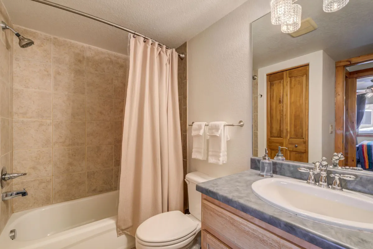 A modern bathroom featuring a bathtub, vanity sink with wooden cabinetry, soft towels, and elegant light fixtures. The space is bright, clean, and serene, ideal for relaxation and self-care.