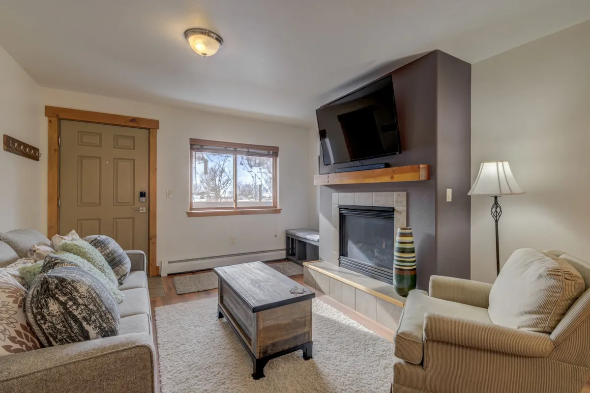 A welcoming living room featuring a stone fireplace, plush sofa, and coffee table. The scene feels comfortable and inviting, suggesting a place to gather and unwind after a day spent exploring outdoors.