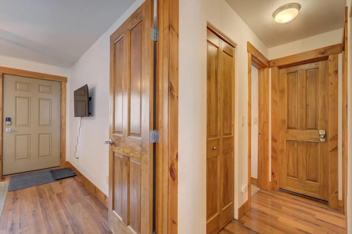 This image shows the front door area flanked by a wall-mounted television and wooden doors, giving a sense of the entryway and the transition point between the outdoors and interior living spaces. The setting is inviting, with details that hint at a warm welcome after a day of winter activities.
